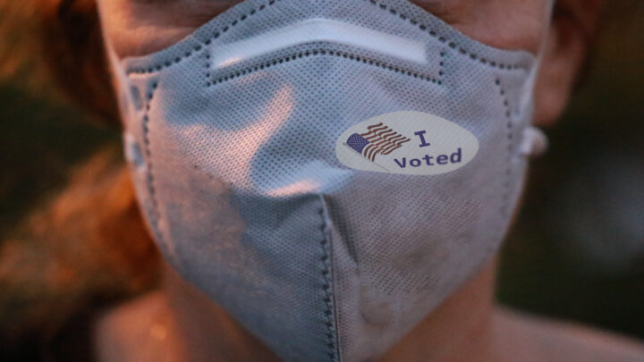 A person dons a gray mask with an "I voted" sticker, reminiscent of the 2020 election fervor that sparked heated Sermo discussions among physicians nationwide.