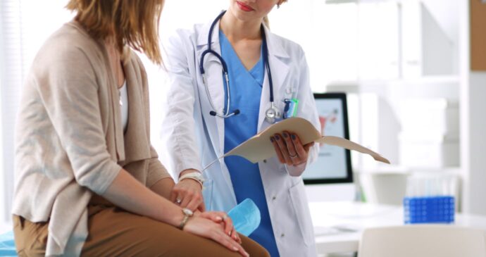 In an office setting, a doctor engages in a thoughtful discussion with a seated patient, holding a file with practiced ease. The stethoscope around the doctor's neck signifies their commitment to effective medical practices.