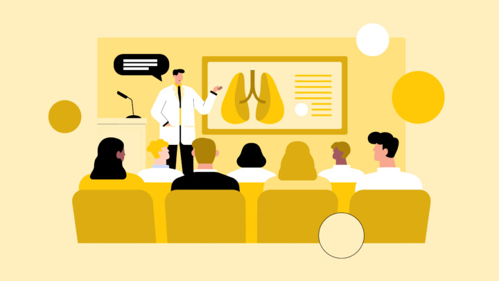Un médico hace una presentación sobre los pulmones ante un público sentado en un aula, con diagramas expuestos en una pizarra.
