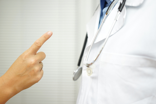 A person points a finger at a doctor wearing a white coat and stethoscope, highlighting the growing concerns surrounding opioids.