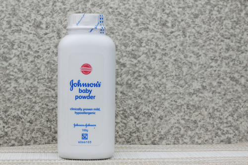 A white bottle of Johnson's baby powder, known for its gentle touch, sits against a textured background.