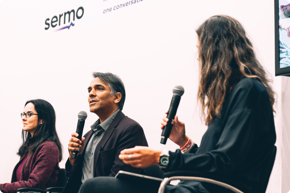 Tres personas sosteniendo micrófonos participan en un panel de discusión de Sermo, deseosas de conocer diversas perspectivas y conocimientos.